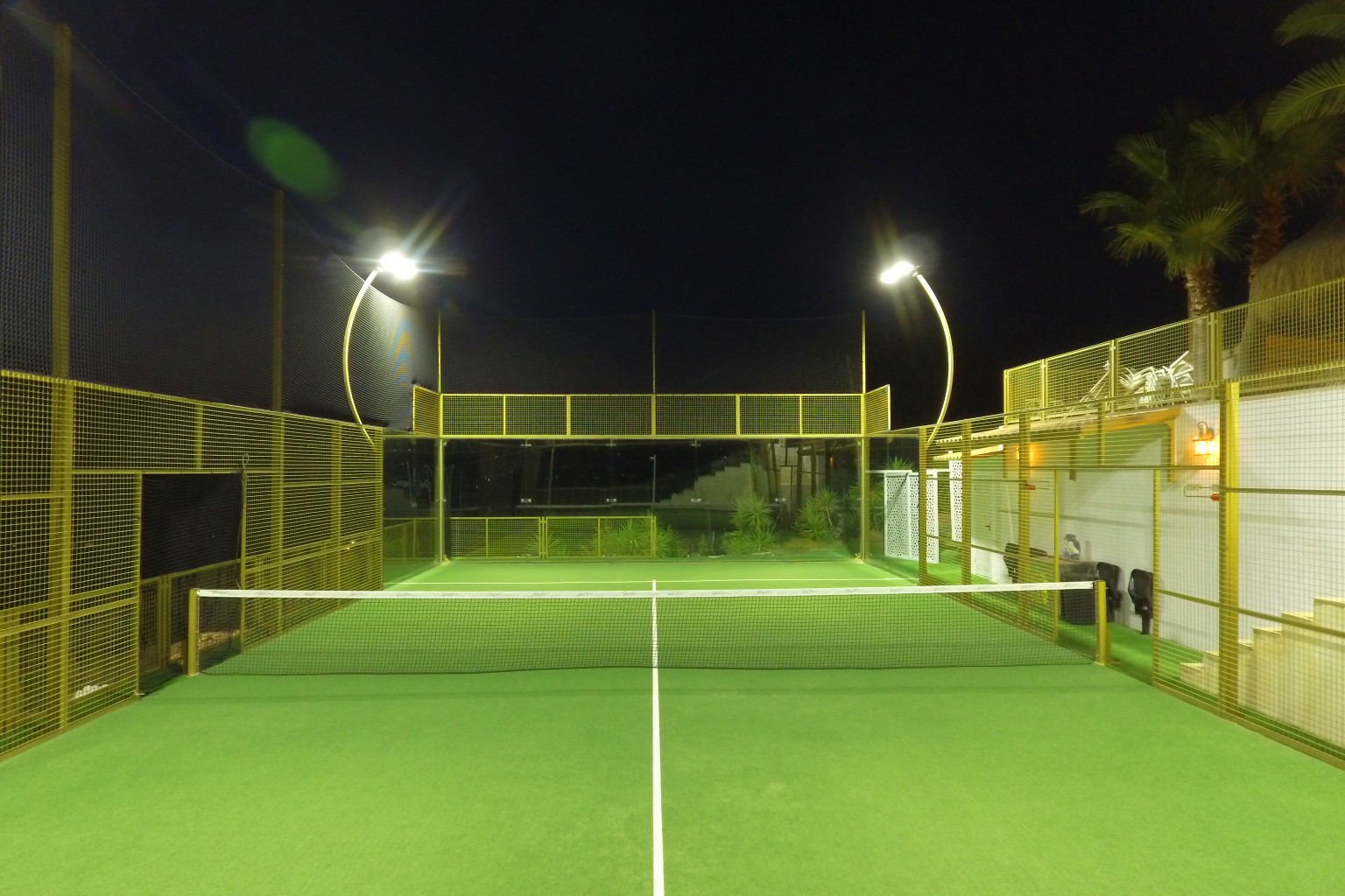 The court from the baseline under floodlight after dark