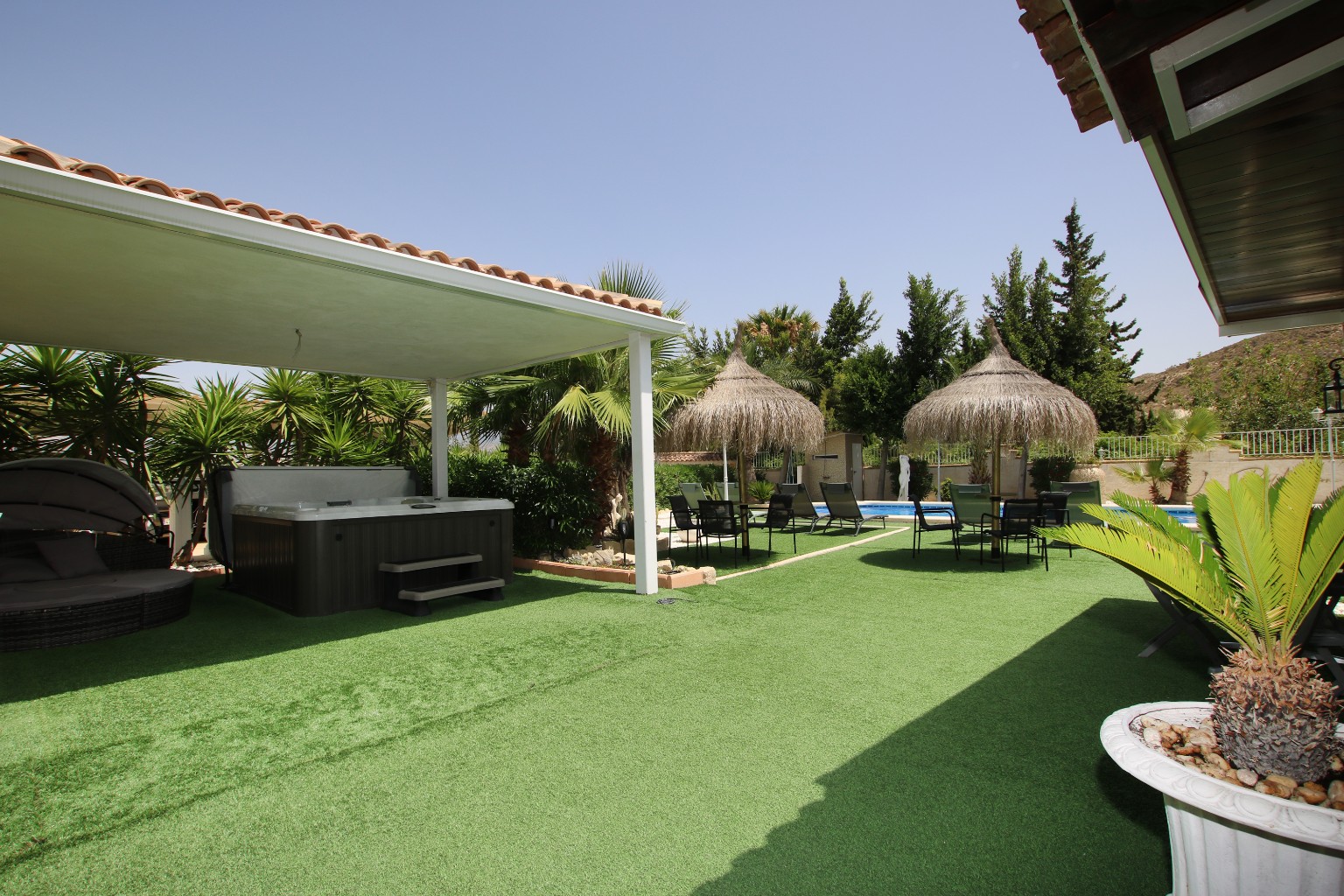 The jacuzzi and its deck seen wide, garden beyond