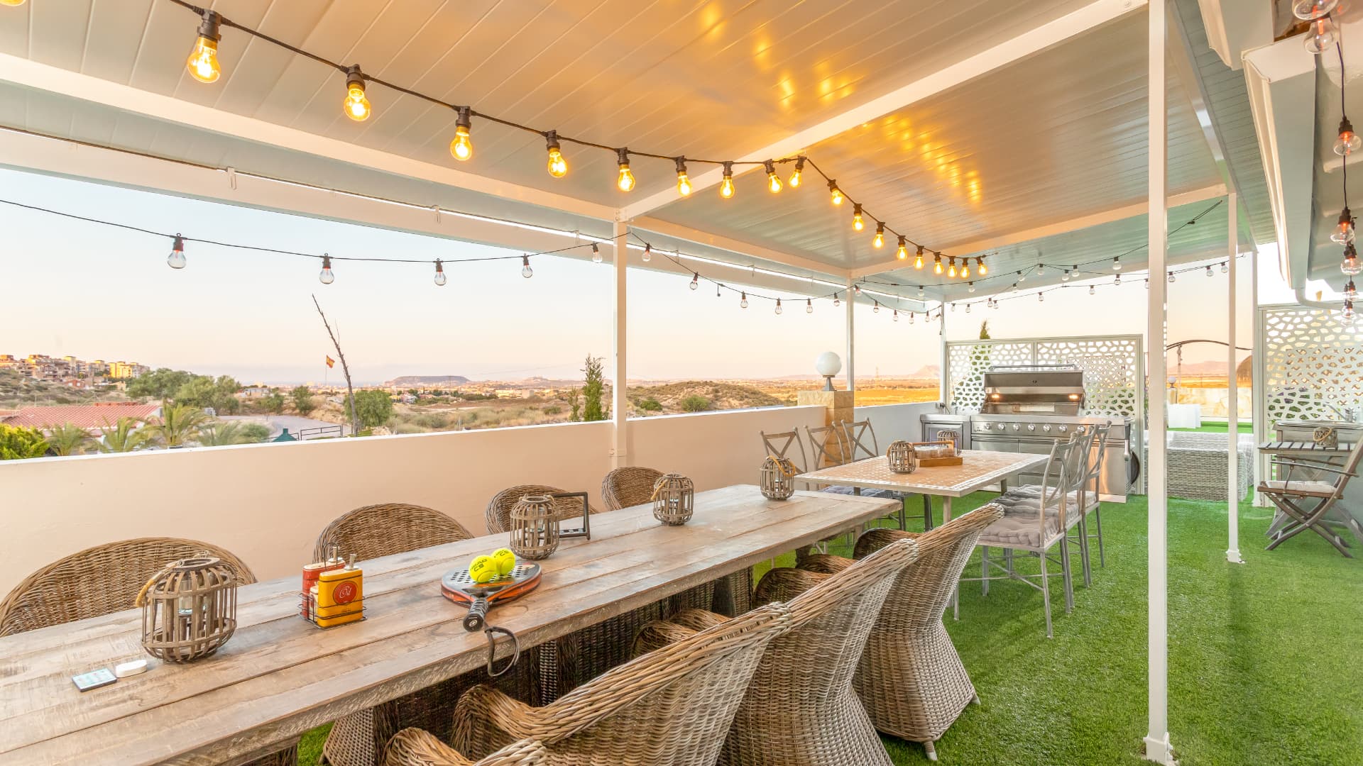 The dining terrace at dusk, long table under strung light